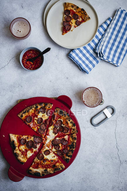 Pizza a lenha com pepperoni e fior di latte, servida com molho de pimenta e cerveja — Fotografia de Stock