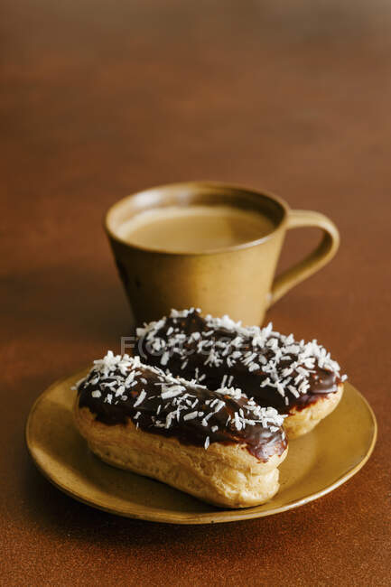 Coconut eclairs and cup of coffee — Stock Photo