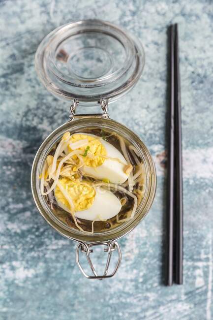 Ramen soup with spinach, bamboo shoots, carrots, egg and mushrooms in a glass jar — Stock Photo