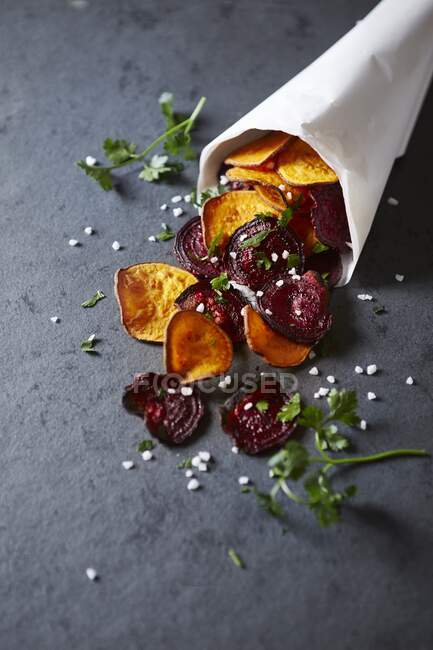 Homemade sweet potato and beetroot crisps in a paper bag — Stock Photo