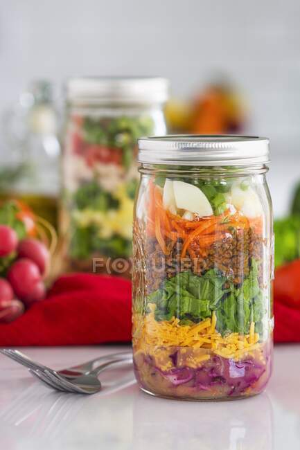 Layered salad in glass jars with spinach, carrots and cheese — Stock Photo