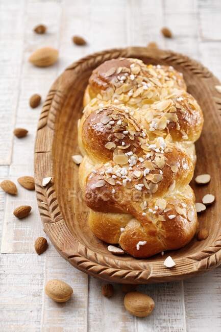 A yeast bread plait with almond flakes in a wooden bowl — Stock Photo