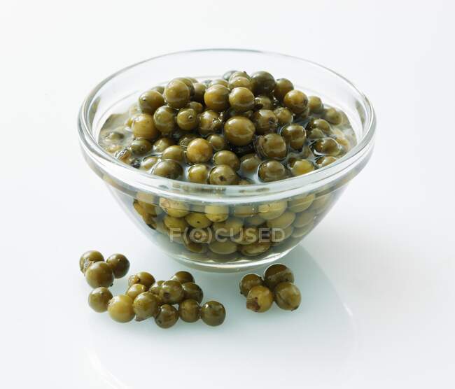 Pickled green peppercorns in a glass bowl — Stock Photo