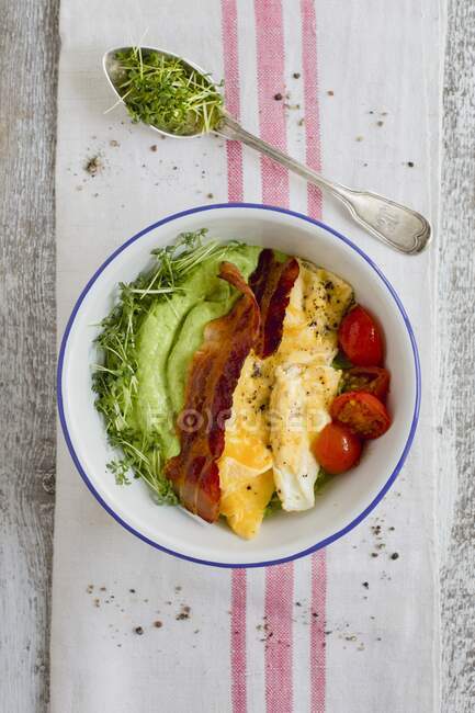 Breakfast bowl with avocado and cucumber cream, scrambled eggs, bacon and tomatoes — Photo de stock