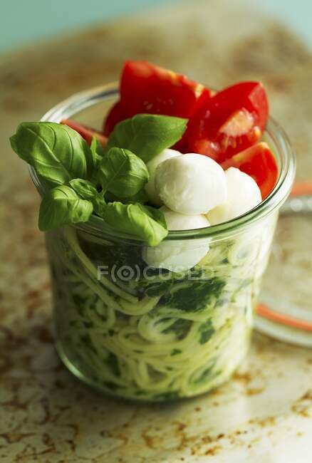 Обед в стеклянной банке: спагетти со шпинатом, моцареллой и базиликом — стоковое фото