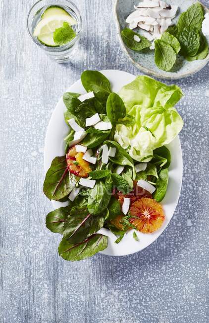 Mixed leaf salad with blood orange, coconut chips and mint — Stock Photo