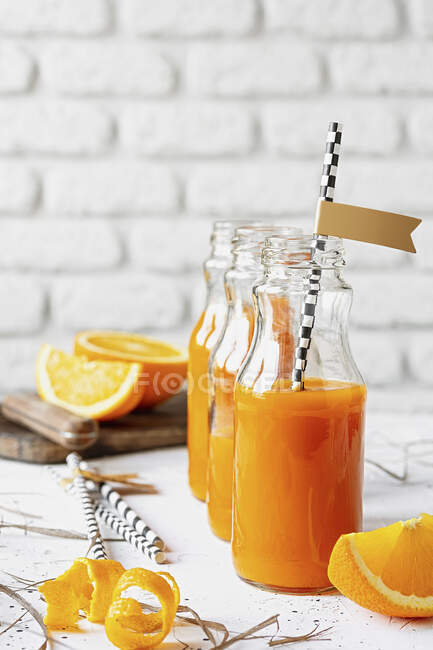 Свіжий вітамінно-оранжевий сік у пляшках на кухонній стійці — стокове фото