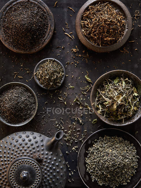 Plan rapproché de délicieuses feuilles de thé différentes avec une théière — Photo de stock