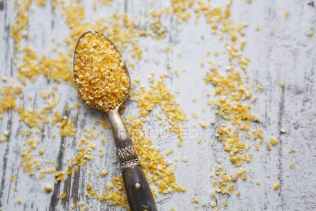 Couscous on a spoon and a wooden background — Stock Photo