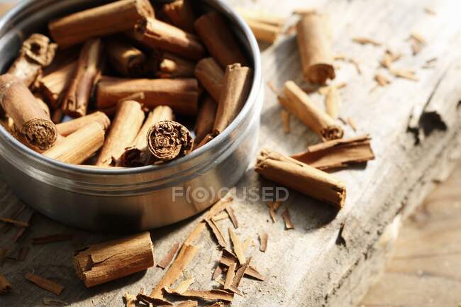 Cinnamon sticks inside and next to a tin on a wooden surface — Stock Photo