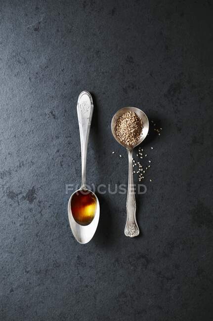 Кунжутное масло и кунжутные семечки на ложках — стоковое фото