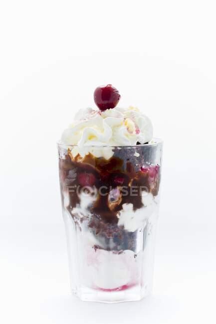 Yogur helado con pastel de chocolate, cerezas, salsa de chocolate y crema - foto de stock