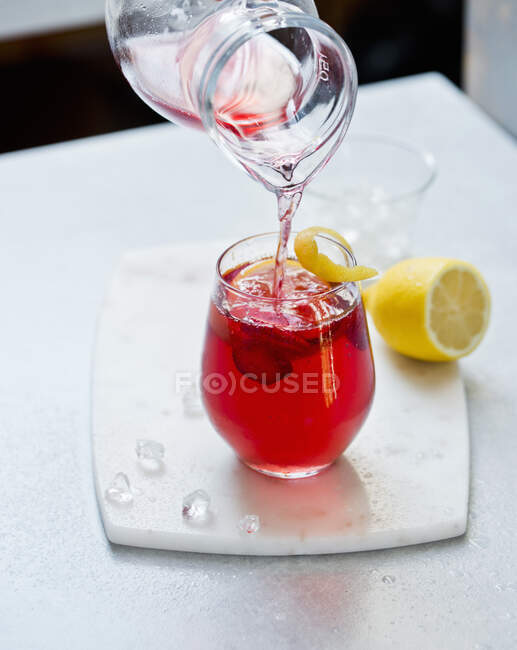 Homemade iced tea is poured from a jug into a glass — Stock Photo