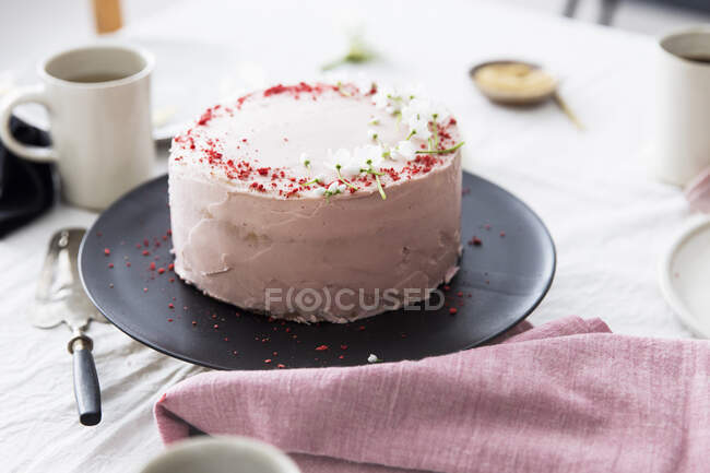 A strawberry cream cake on table laid for coffee — Stock Photo