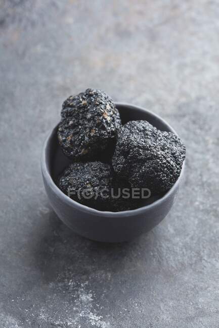 Three black truffles in a grey bowl — Stock Photo