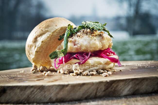 Burger with cabbage on a tree stump outdoors (camping) — Stock Photo