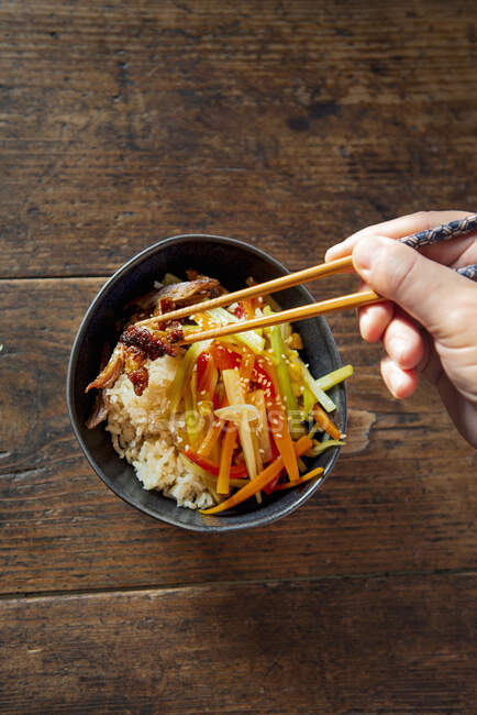 Hands taking Chinese vegetable and duck stir fry with chopsticks, top view — Stock Photo