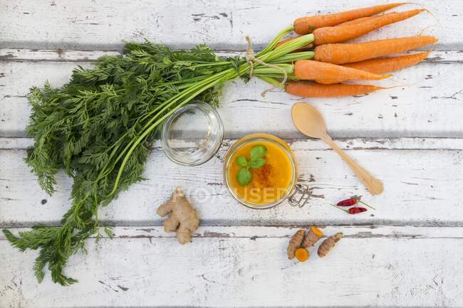 Морковный суп с куркумой, имбирем и чили в банке на перевернутой крышке — стоковое фото
