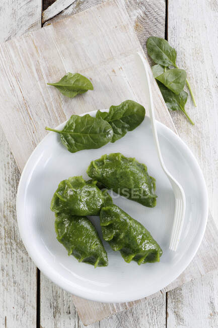 Green spinach leaves in a bowl on a wooden background — Stock Photo