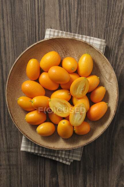 Fresh kumquats in a wooden bowl (top view) — Stock Photo