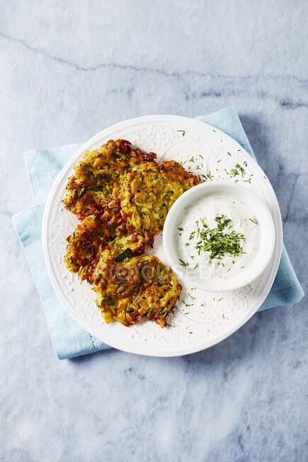Sweet potato and zucchini fritters with a herb yoghurt dip (top view) — Stock Photo