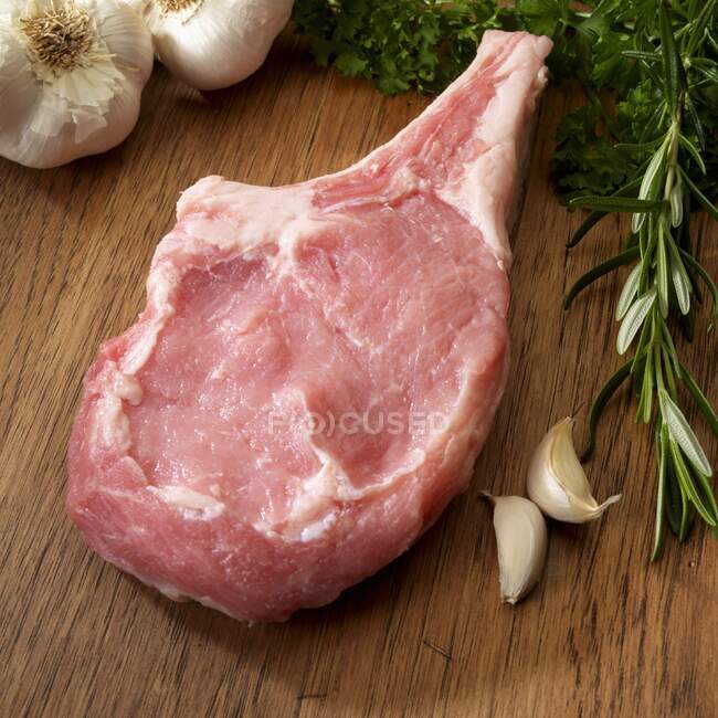 One raw Veal Chop with herbs and garlic on cutting board — Stock Photo