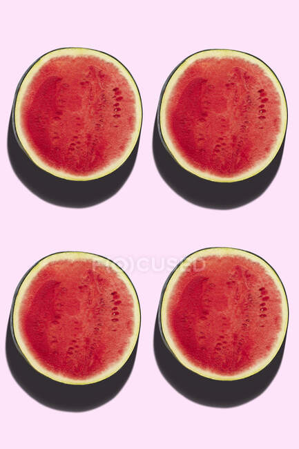 Quatro metades de melancia no fundo rosa — Fotografia de Stock
