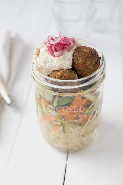Vegan couscous salad with falafel, carrots, zucchini, hummus and red onions — Stock Photo