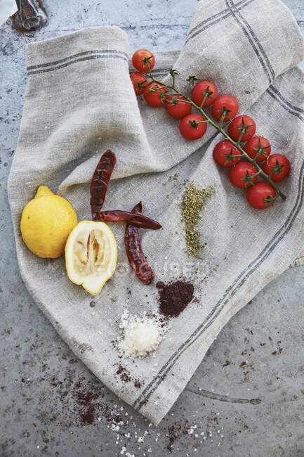 Limoni, pomodori, peperoncini e spezie su un panno di lino — Foto stock