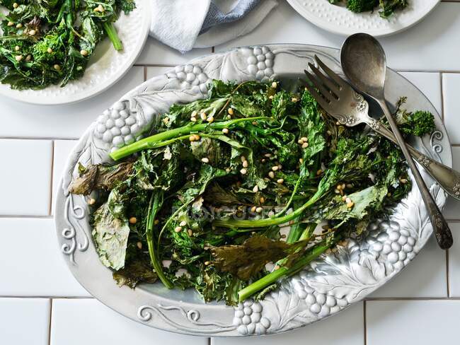Fried broccolini with pine nuts on a vintage serving plate — Stock Photo