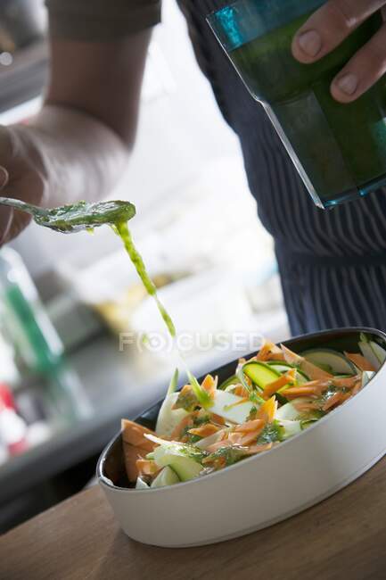 Ein Gemüsesalat wird mit Dressing beträufelt — Stockfoto