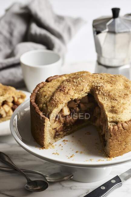 Apple pie, partly sliced on cake stand — Stock Photo