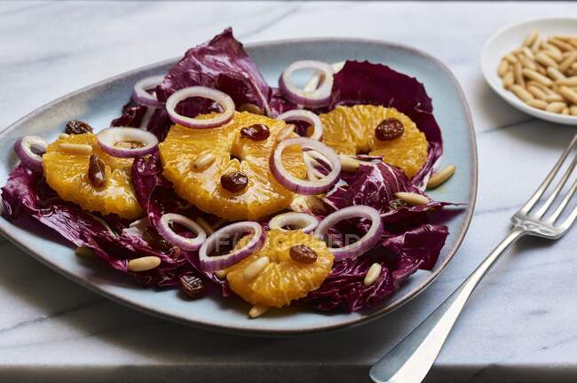 Wintery radicchio salad with oranges, red onions, raisins and pine nuts — Stock Photo