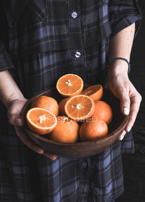 Woman holding bowl with oranges — Stock Photo