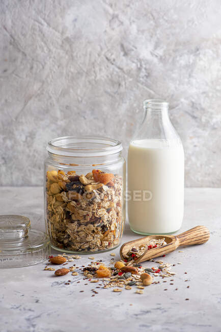 Домашние орехи, семена и фрукты мюсли в банке с молоком — стоковое фото