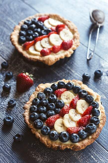 Fruit tarts with strawberries, blueberries and banana slices — Stock Photo
