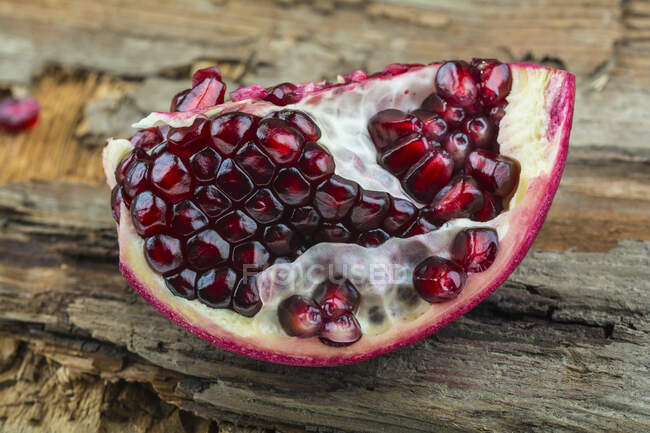 A piece of pomegranate on a wooden surface — Stock Photo