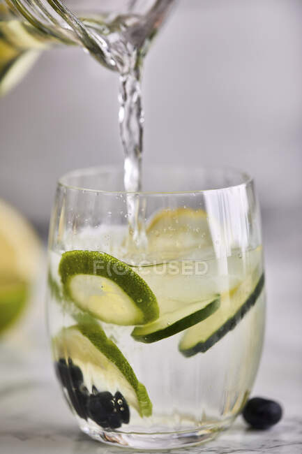 Verser de l'eau fraîche infusée froide dans un verre — Photo de stock