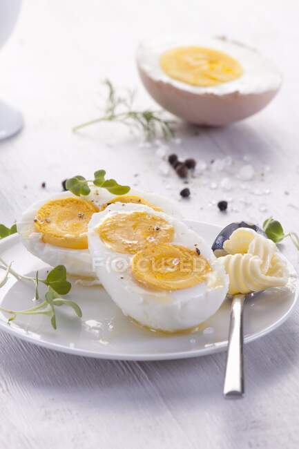 Huevo cocido a la mitad con dos yemas y cuchara con mantequilla en el plato - foto de stock