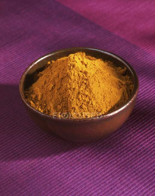 Curry powder in a small bowl on a pink tablecloth — Stock Photo