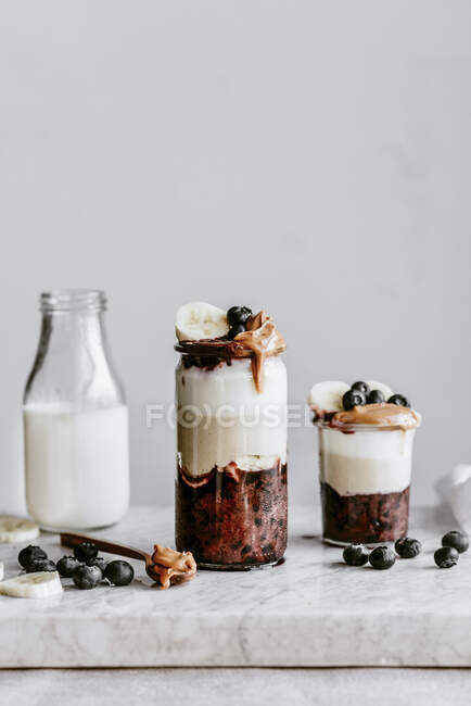 Desserts in jars with blueberries, peanut butter and banana mousse — Stock Photo