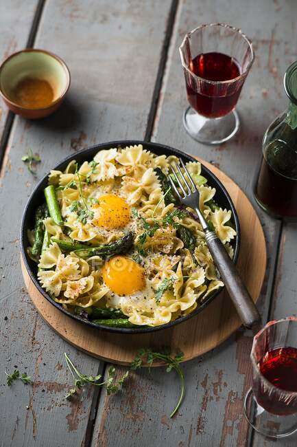 A pasta dish with asparagus and fried eggs — Stock Photo