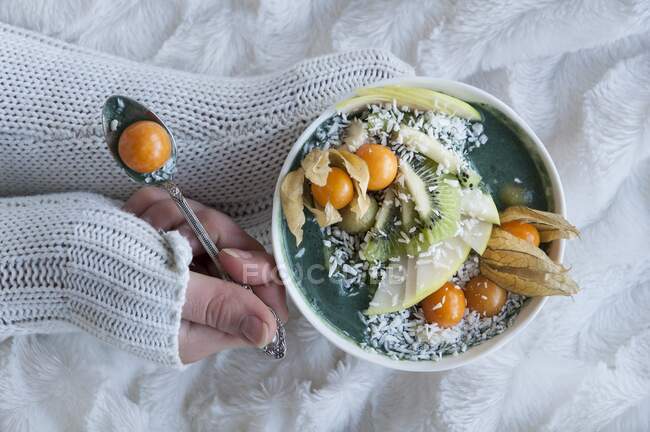 A green smoothie bowl with physalis, kiwi, apple and coconut flakes — Stock Photo
