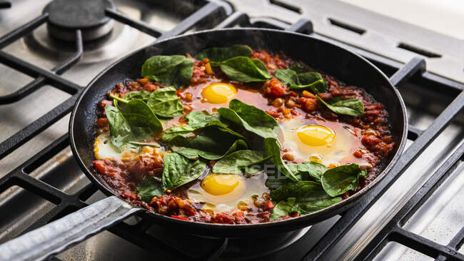 Shakshuka with spinach cooking in pan — Stock Photo