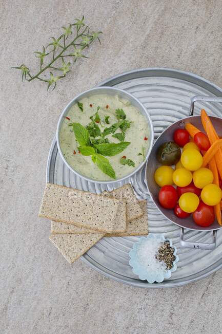 Herb houmous on a tray with colourful tomatoes and crispbread — Stock Photo