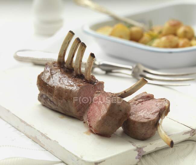 A rack of lamb with roast potatoes — Stock Photo