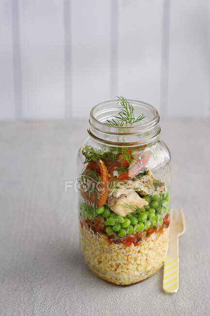 Insalata di cous cous con pesce, piselli e pomodori in barattolo di vetro — Foto stock
