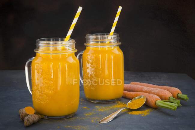 Cenoura e smoothie açafrão em dois copos com palhas — Fotografia de Stock