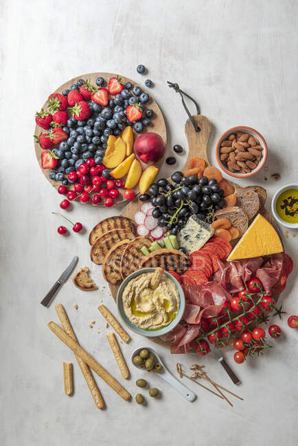 Делі тарілка з шинкою, сиром, гумусом, оливками, свіжими фруктами та хлібом — стокове фото