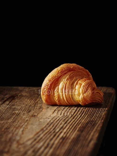 Ein Croissant auf einem Holzbrett — Stockfoto